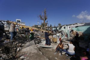 Varias personas permanecen alrededor de sus destruidos hogares el 28 de enero, en un barrio del municipio de Regla, mientras trabajadores laboran en la reconstrucción de las viviendas, dañadas por el tornado que el día antes azotó cinco de los 15 municipios de la capital de Cuba. Crédito: Jorge Luis Baños/IPS